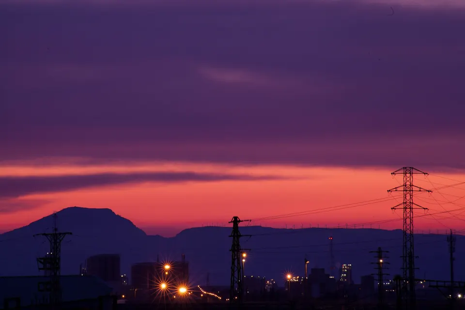 Captivating industrial skyline at dusk with vivid pink and purple sunset hues.