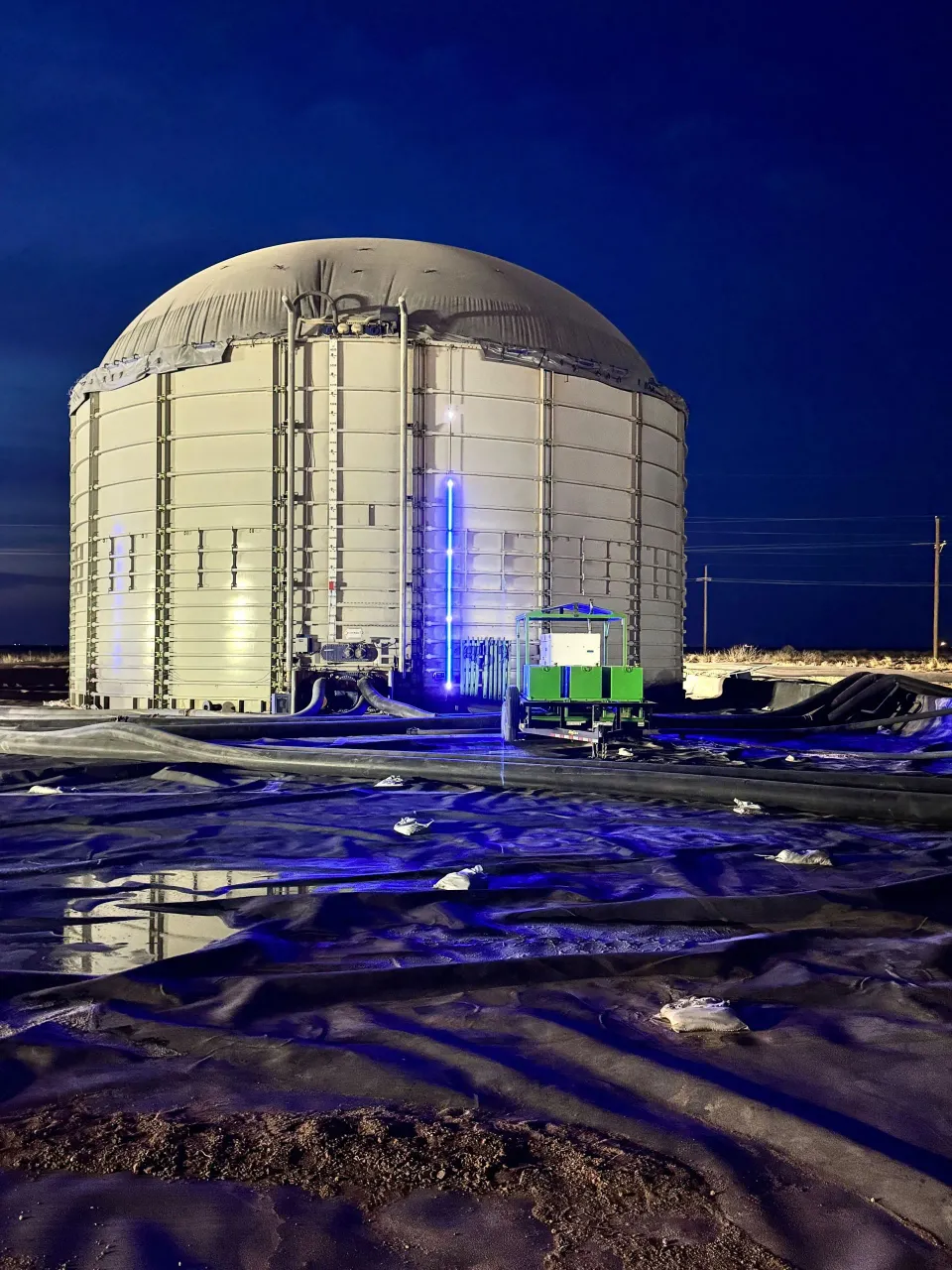A domed storage tank at night with a blue SHIELD LED level indicator and control unit