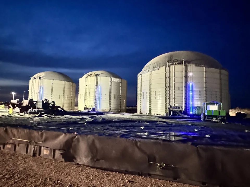 Three domed frac tanks at night, each fitted with a SHIELD LED level indicator bar